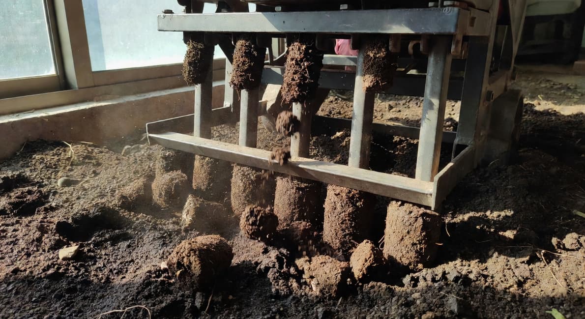 園藝師操作深翻機打孔曝氣土壤，踩踏橫檔施力並排出土芯。