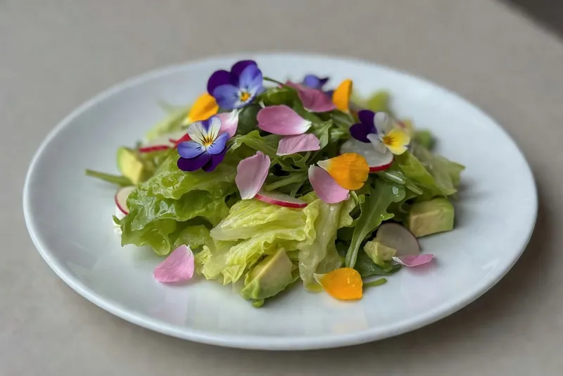 白盤子上新鮮沙拉裝飾著可食用花瓣，增添視覺魅力。