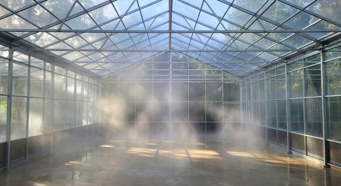 溫室內壁地面噴灑消毒液，霧氣瀰漫，空蕩骨架清晰，準備新一季種植乾淨感